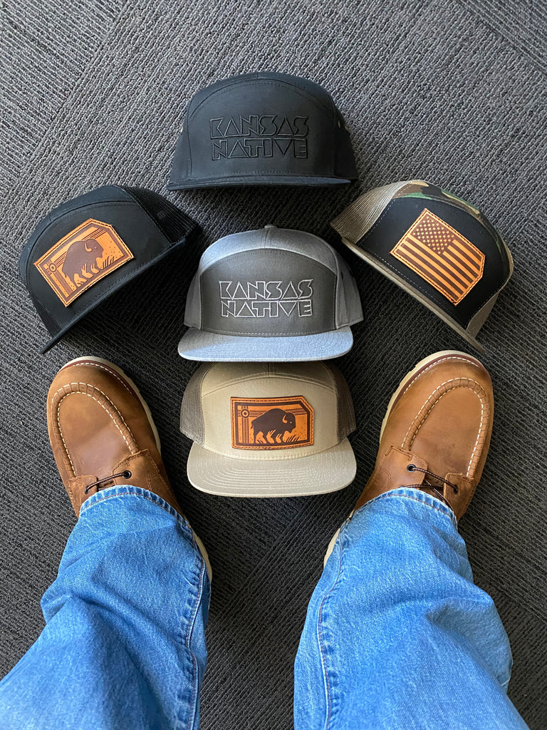 Numerous Kinfolk hats displayed around a pair of work boots.