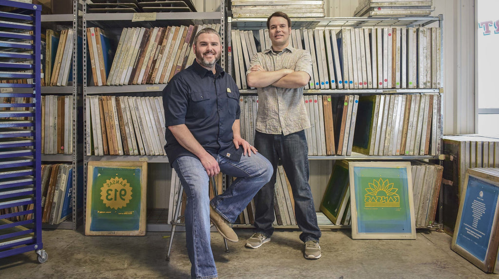 Kinfolk designers Bryan Lisbona and Toby Kuhn pose for a photo in front of numerous screens at their print shop.